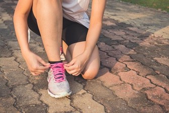 Now's your chance to start cultivating healthier habits. A woman lacing up her running shoes.